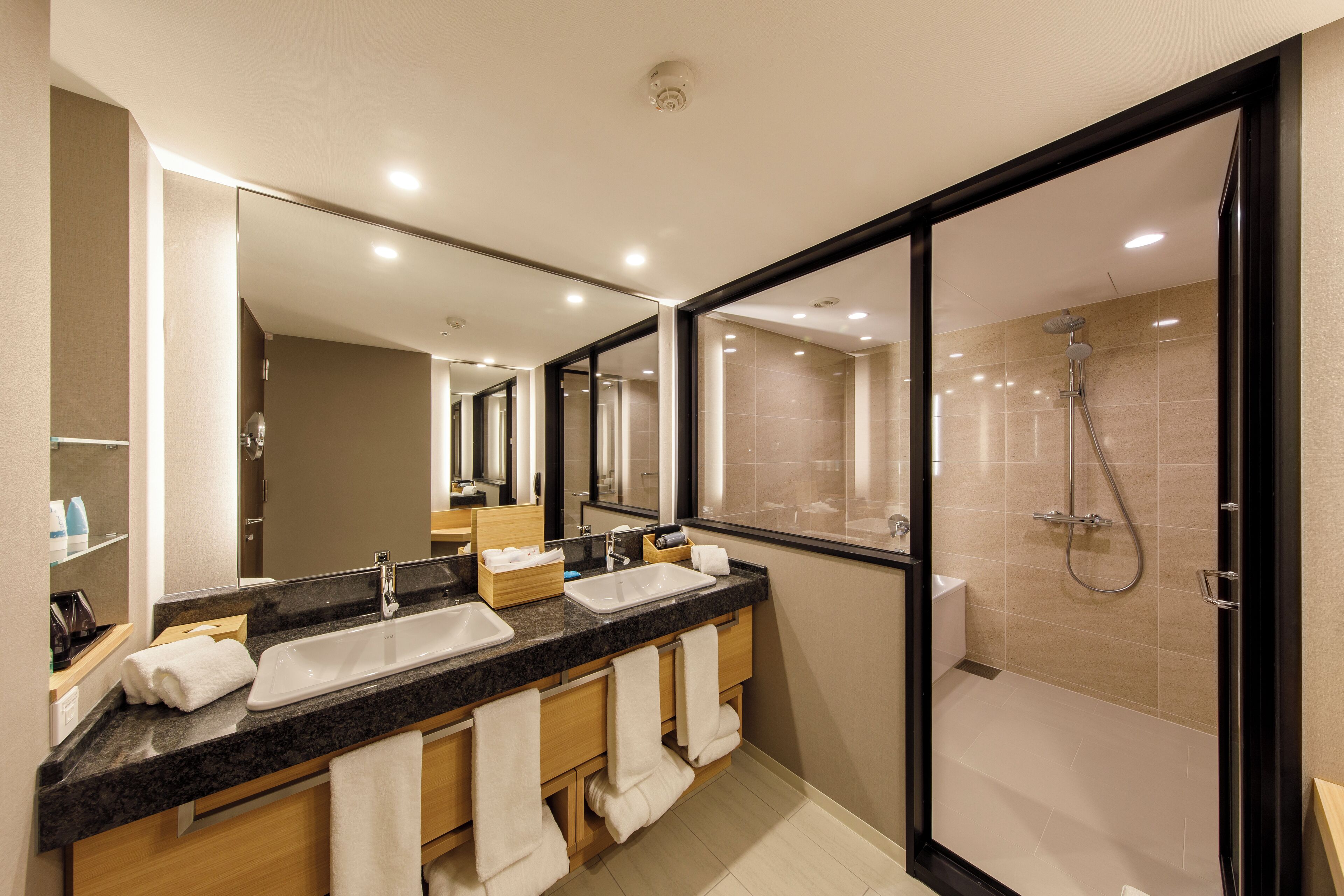 Een moderne badkamer met een dubbele wastafel, een grote spiegel en een douche met glazen wanden.