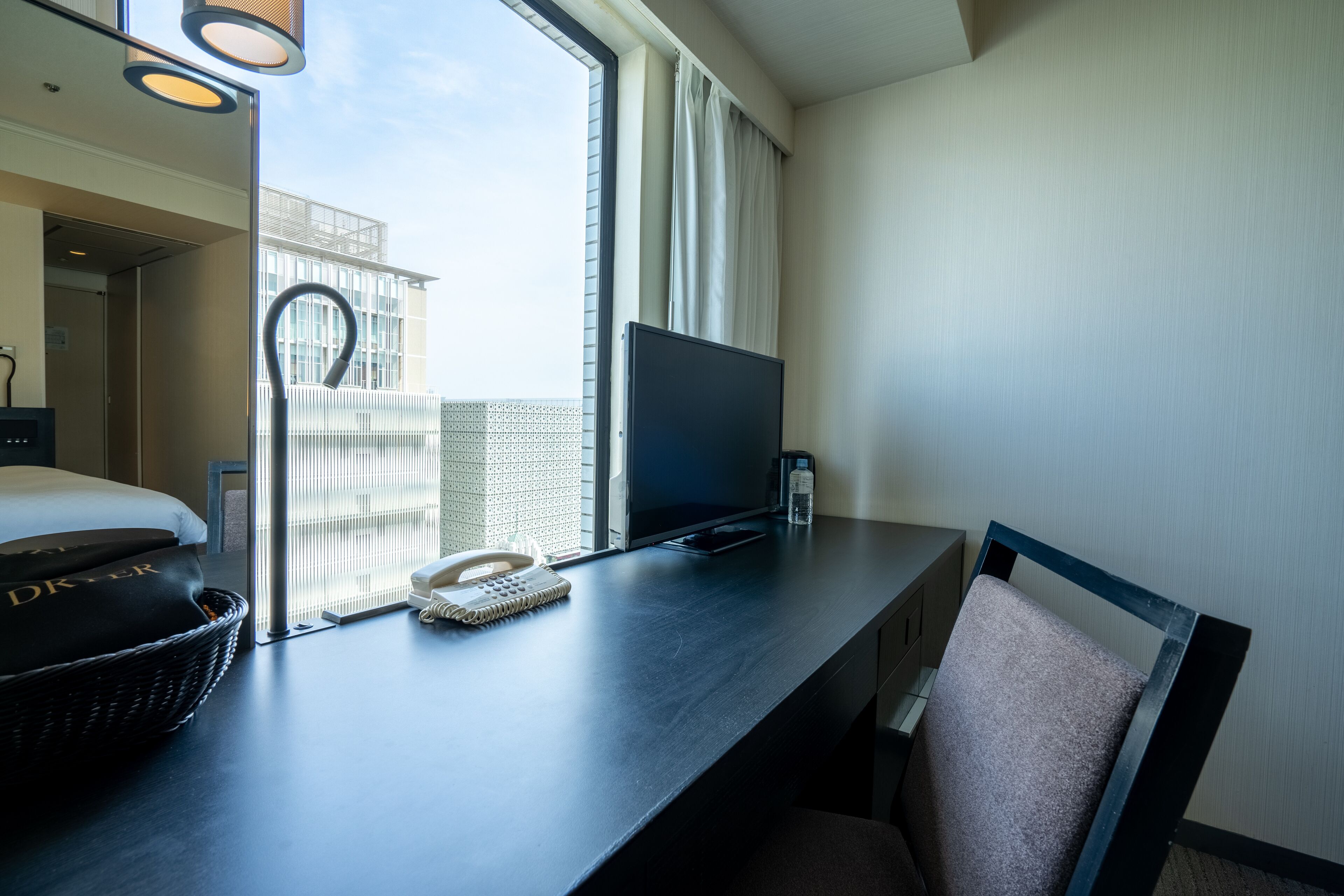 Une chambre d’hôtel comprenant un lit, un bureau avec un téléphone, une télévision et une chaise.