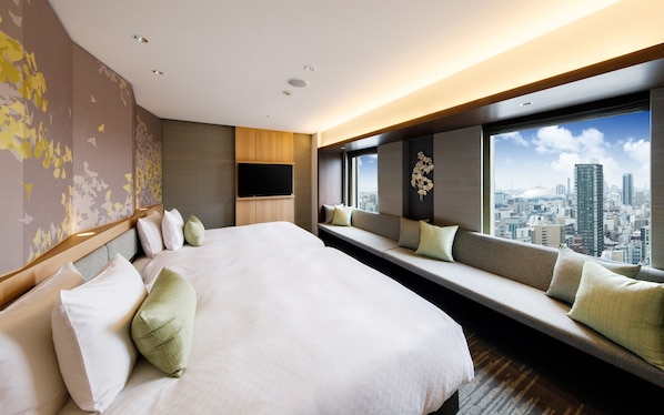 Ein modernes Hotelzimmer mit einem großen Bett, integriertem Fernseher und Blick auf die Stadt.