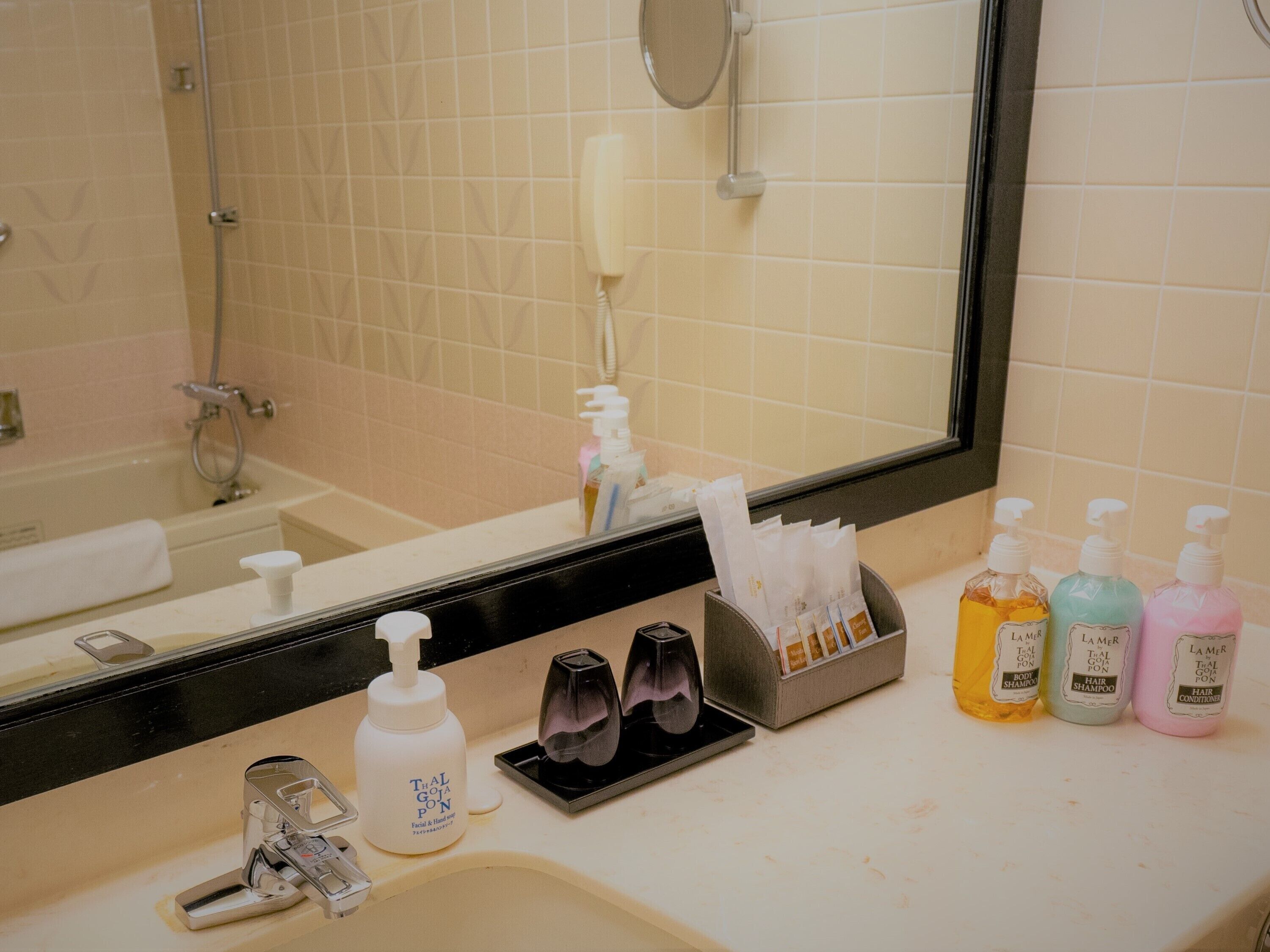 A bathroom with a bathtub, a sink with a mirror, and various toiletries including shampoo and conditioner bottles.