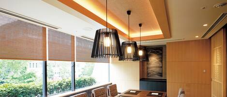 A conference room with a long table, patterned chairs, and pendant lighting.