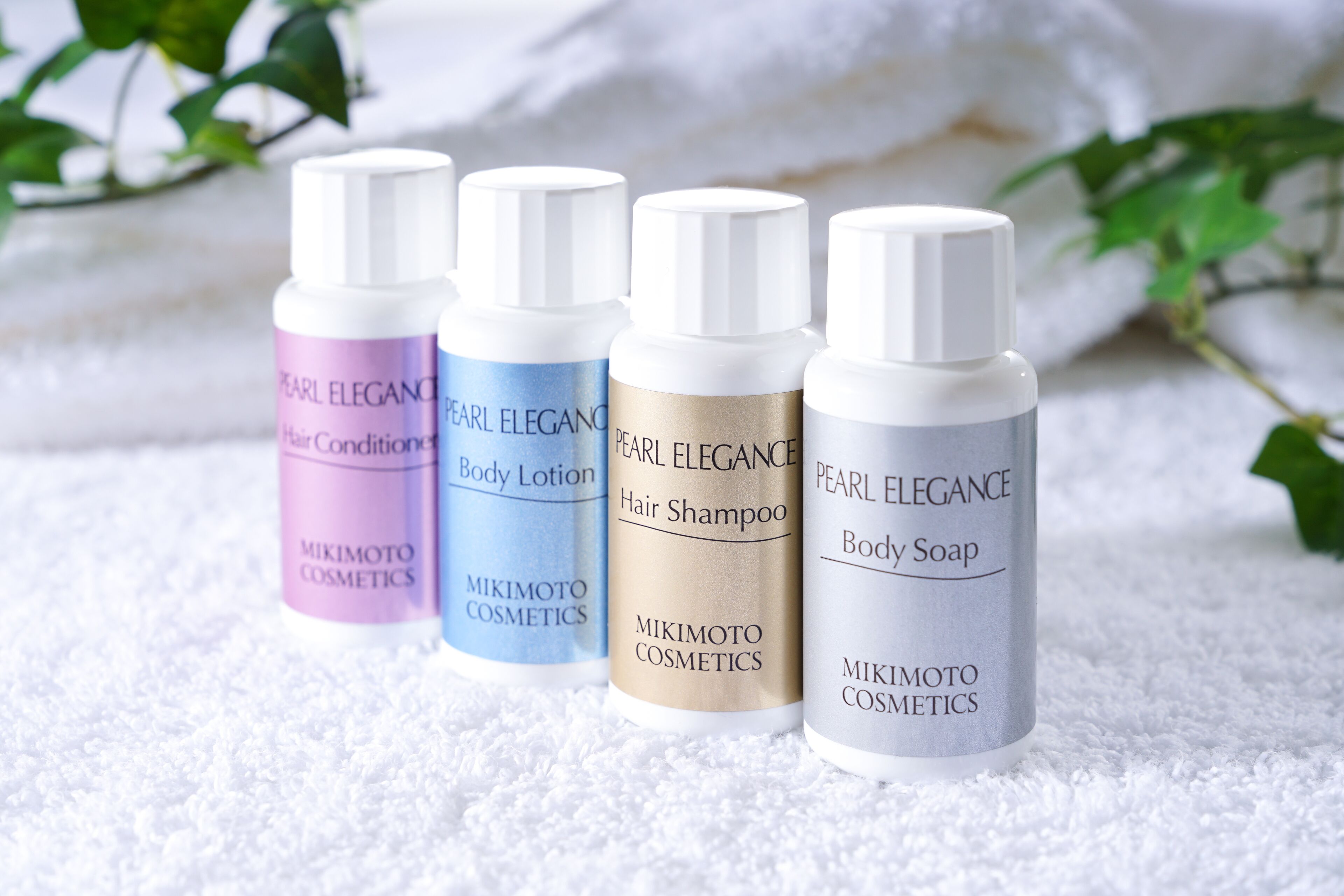 Four bottles of Pearl Elegance skincare products on a white textured surface.