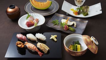 Variedad de platos de sushi y un melón sobre una mesa oscura.