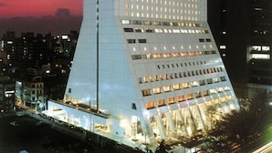 Un hotel moderno y alto, con una base triangular distintiva y numerosos ventanales.