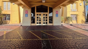 Een gebouw ingang met een overdekte doorgang, een gebied met bakstenen bestrating en een bord dat aangeeft dat parkeren niet is toegestaan.