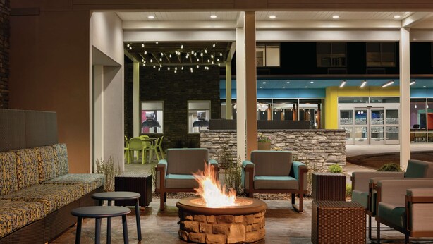An outdoor seating area with a fire pit, sofas, and chairs. - Home2 Suites by Hilton Williamsville Buffalo Airport (Buffalo)