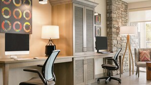 A modern office space with a desk, two chairs, a computer, and a lamp. - Home2 Suites by Hilton Williamsville Buffalo Airport (Buffalo)