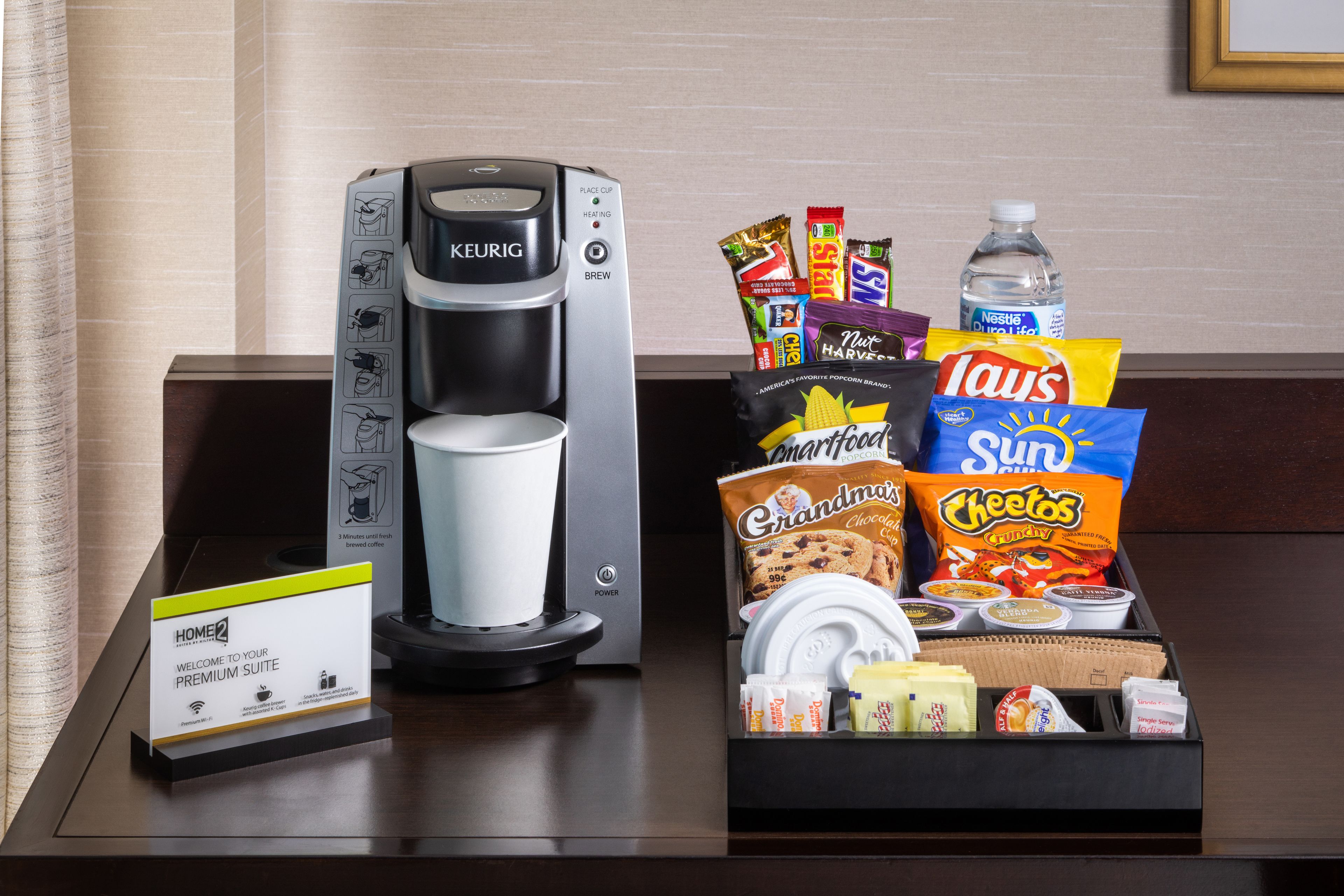Une machine à café, un panneau et un plateau de collations avec des chips et des biscuits.