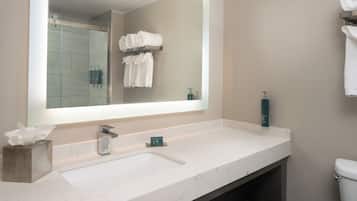 Une salle de bain avec un grand miroir, un lavabo en marbre, un porte-serviettes avec des serviettes pliées et des toilettes.