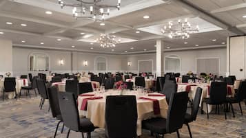 Un amplio salón de banquetes con mesas redondas, sillas negras y candelabros.