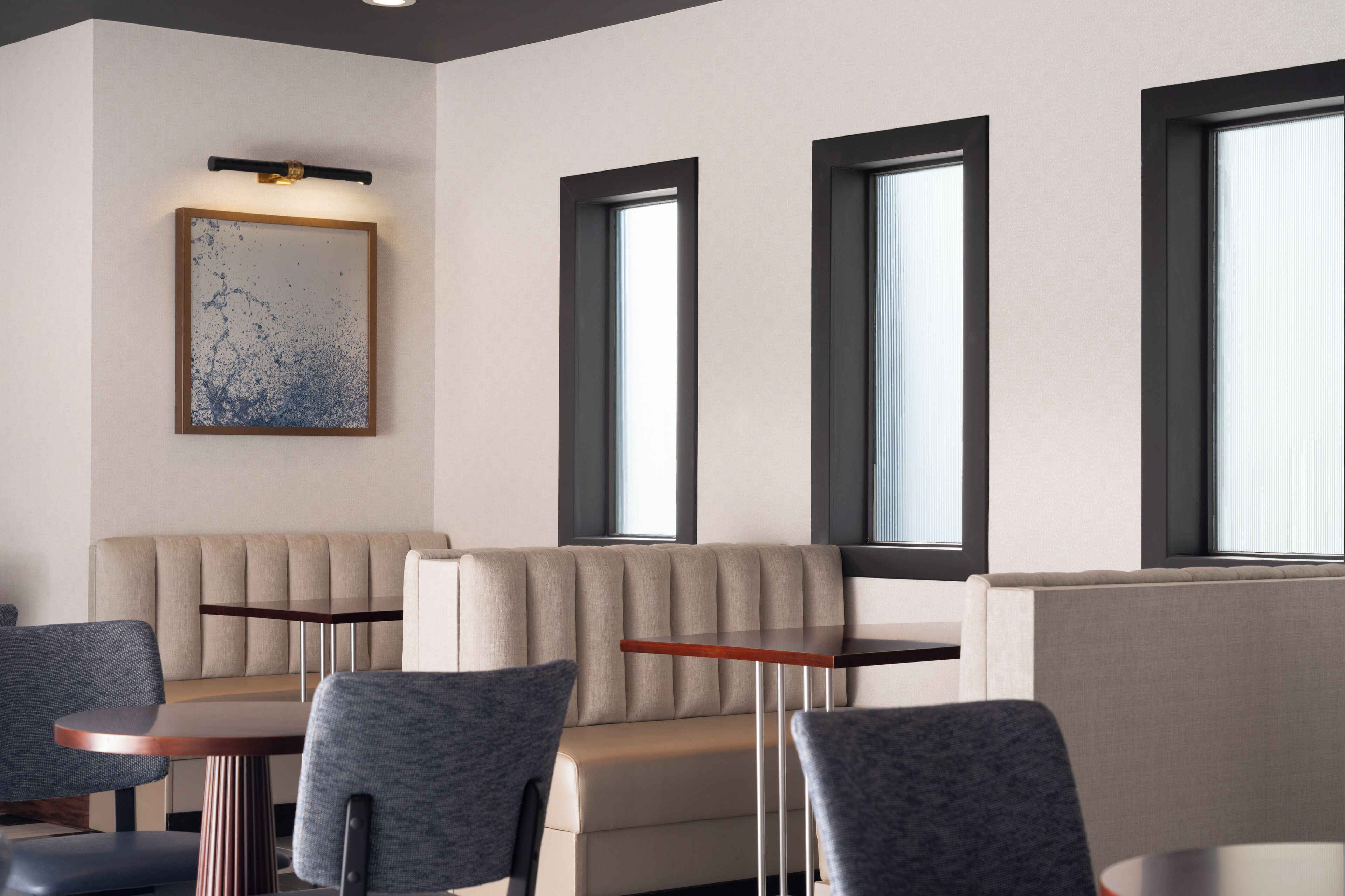Un interior moderno con sofá, sillas y una mesa, con ventanas amplias y un aplique de pared.