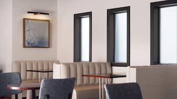 Un interior moderno con sofá, sillas y una mesa, con ventanas amplias y un aplique de pared.