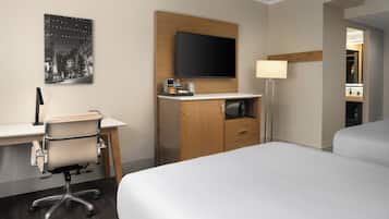A hotel room with a bed, a desk with a chair, a flat-screen TV, a lamp, and a mirror.