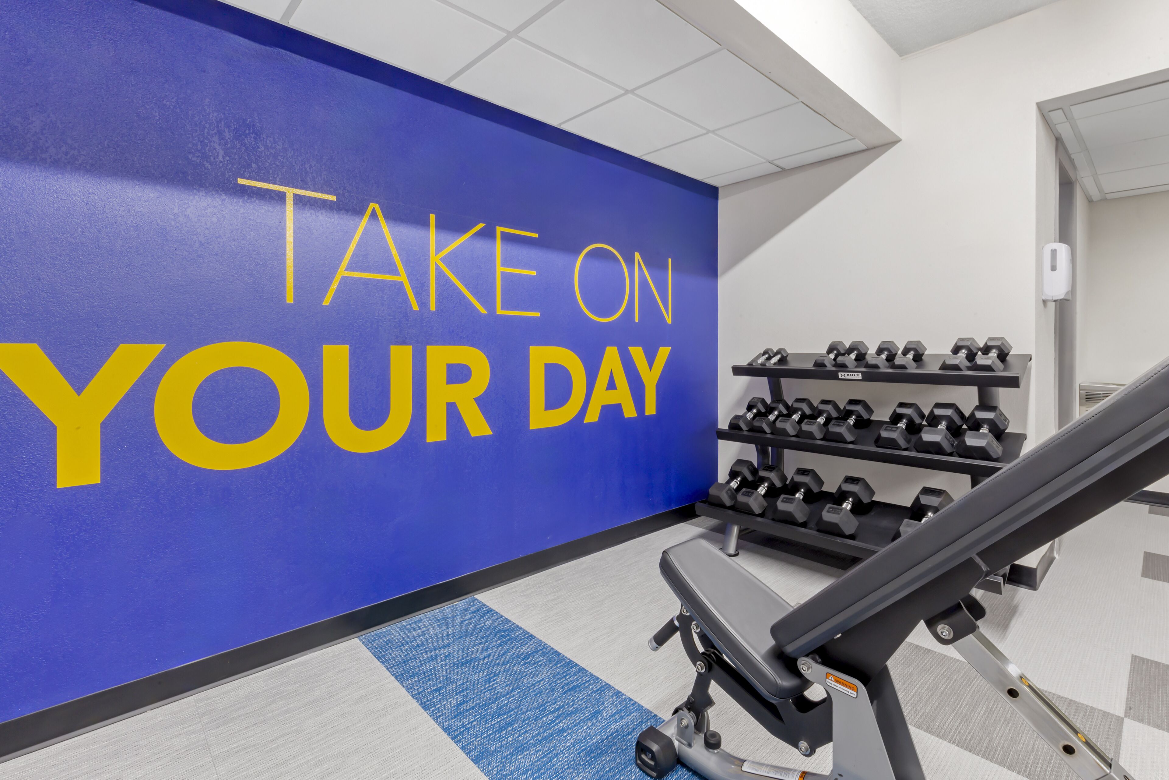 Ein Fitnessstudio mit einer motivierenden Wand, Gewichtsständern und Trainingsgeräten.
