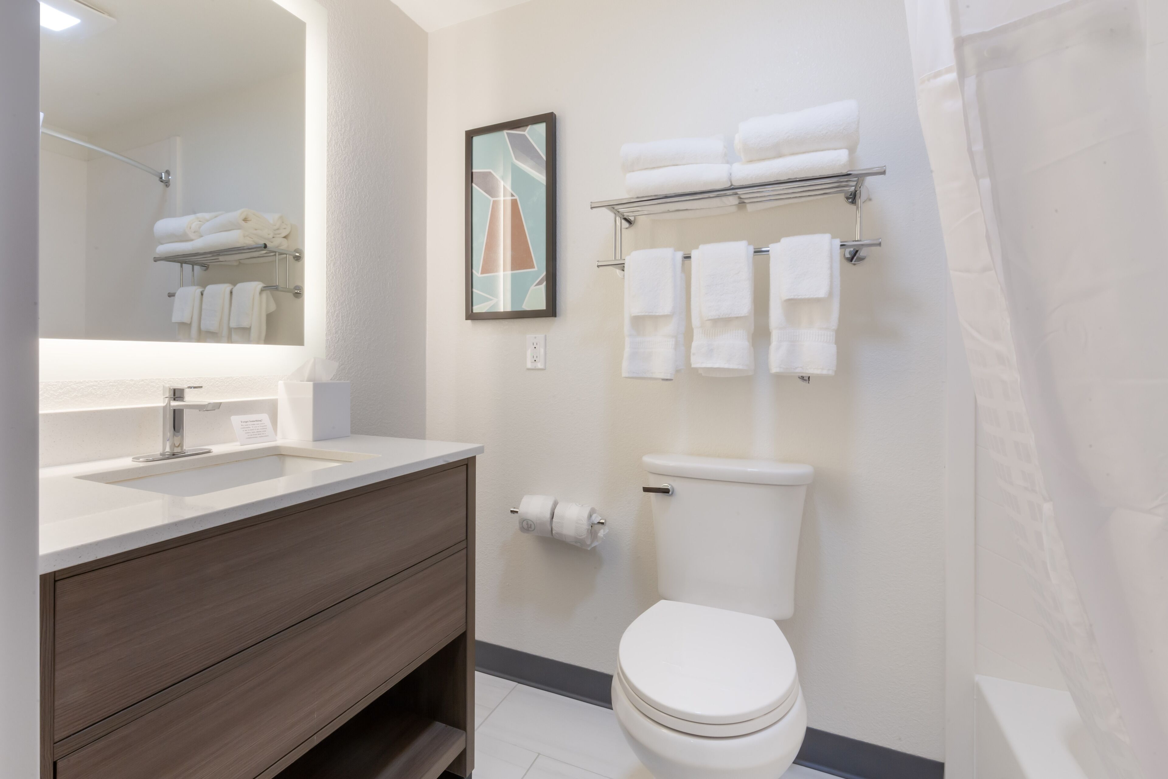 A modern bathroom with a sink, vanity, toilet, and towel rack.