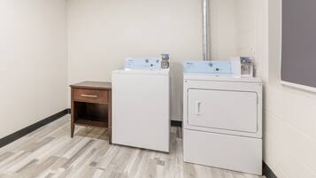 A laundry room with two stacked washers and dryers, a wooden cabinet, and a white wall.