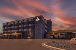 Edifício Comfort Inn & Suites com fachada de pedra, várias janelas e estacionamento.
