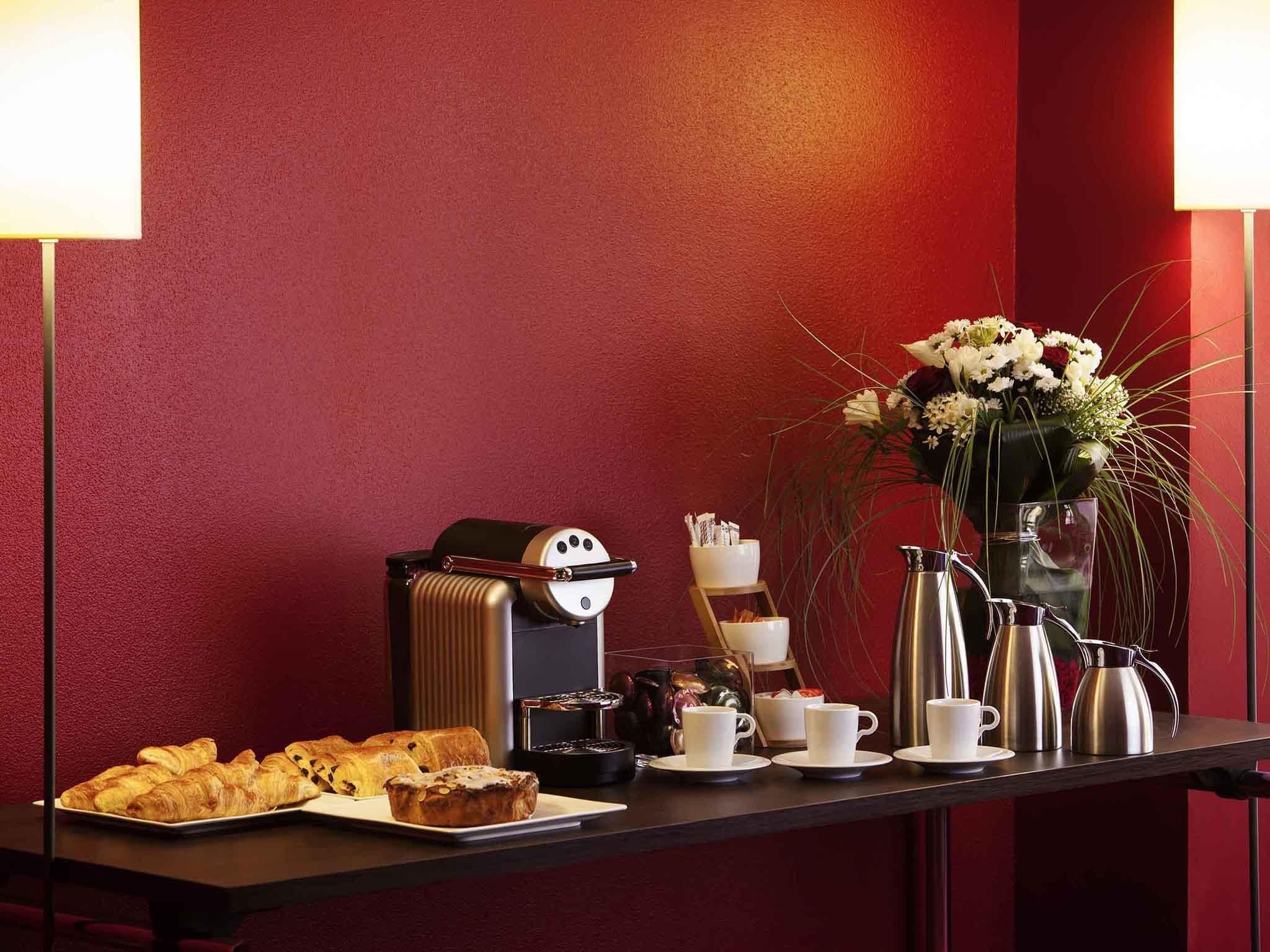 A breakfast setup with pastries, coffee-making equipment, and a vase of flowers.