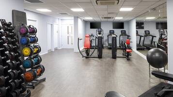 A gym with various exercise equipment, including treadmills, a stationary bike, and a bench.