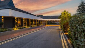 A modern hotel with a covered walkway, landscaped gardens, and a clear sky. - Holiday Inn Reading South M4 Jct11 by IHG (Reading)