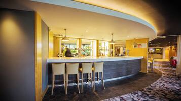 A bar area with a curved counter, three bar stools, and a bartender.