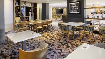 En modern hotellobby med flera sittgrupper, inklusive bord och stolar, och en mönstrad matta.