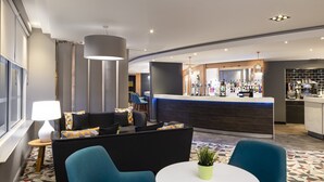 A modern hotel lobby with a bar area, seating arrangements, and a patterned floor. - Holiday Inn Reading South M4 Jct11 by IHG (Reading)