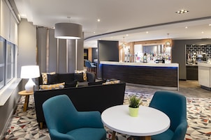 A modern hotel lobby with a bar area, seating arrangements, and a patterned floor.