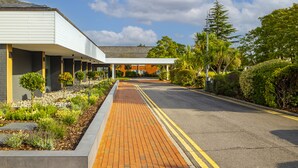 A modern building with a covered walkway and a landscaped garden. - Holiday Inn Reading South M4 Jct11 by IHG (Reading)