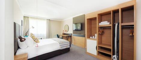 A hotel room with a bed, a desk, a TV, a wardrobe, and a bathroom.