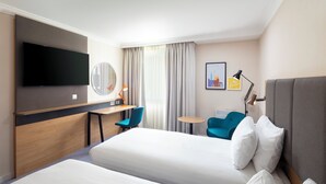 A hotel room with two beds, a desk, a chair, a TV, a lamp, and a small table. - Holiday Inn Reading South M4 Jct11 by IHG (Reading)