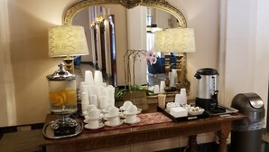 Una zona de recepción de hotel con servicio de té y jerez, una cafetera y un cubo de basura.