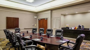 A conference room with a long table, multiple chairs, a reception desk, and a door.