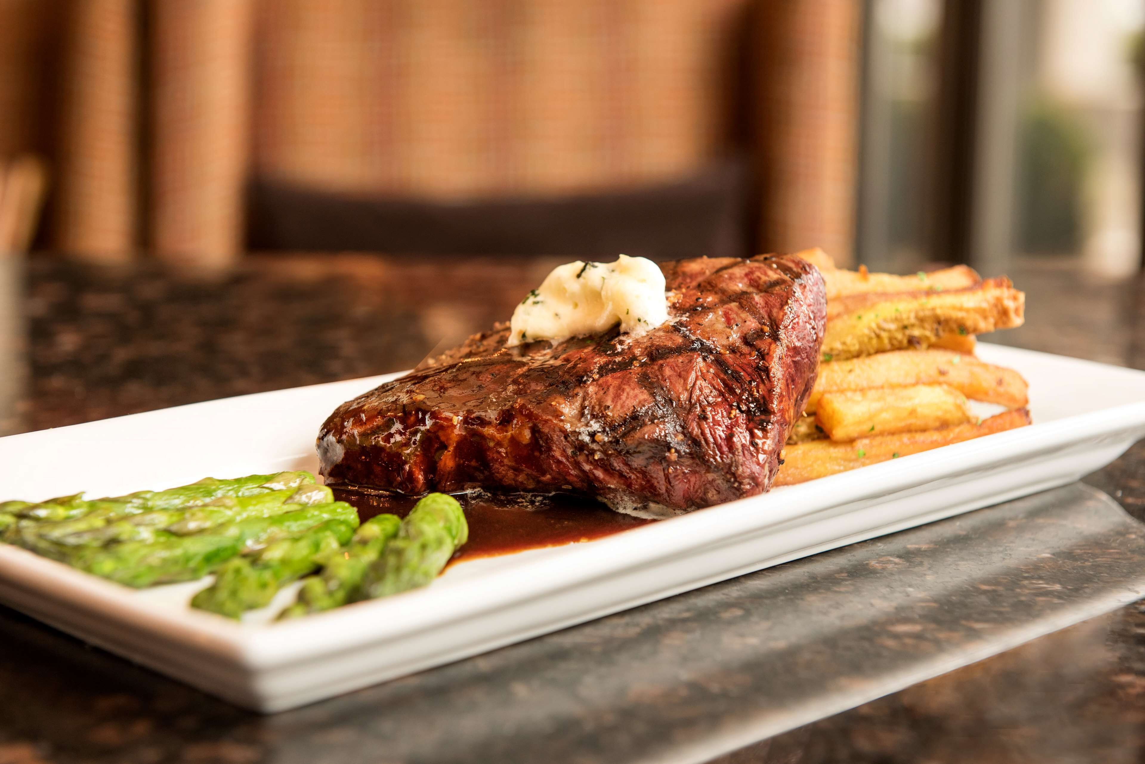 A steak with butter and asparagus on a plate.