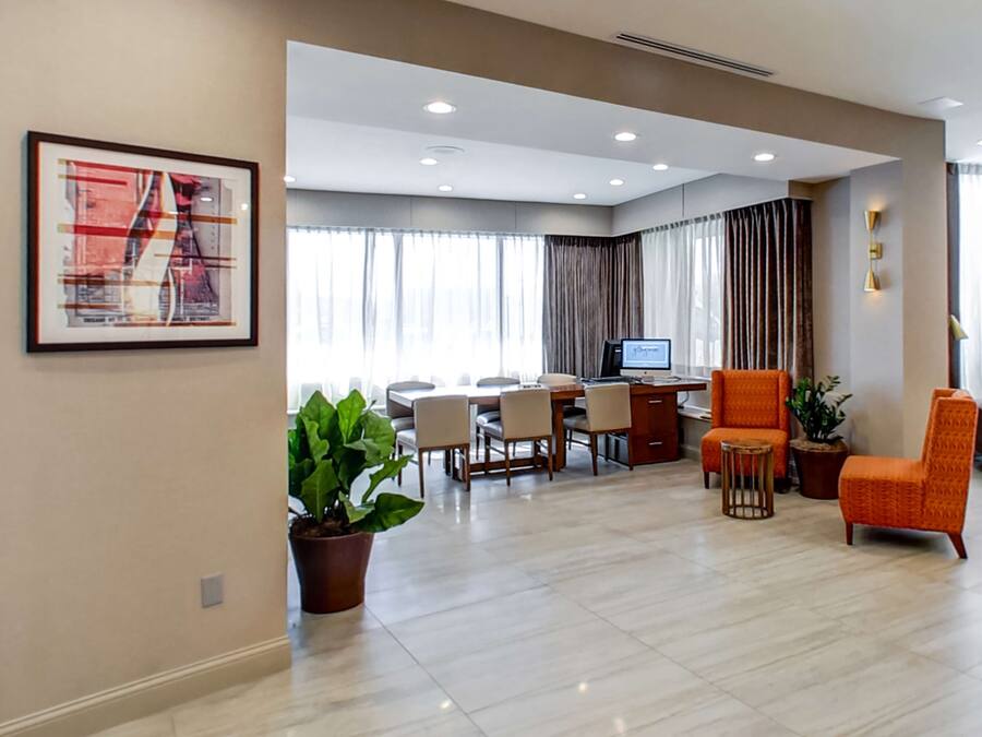 A spacious living area with a dining table, comfortable seating, a computer desk, and a large window with curtains.
