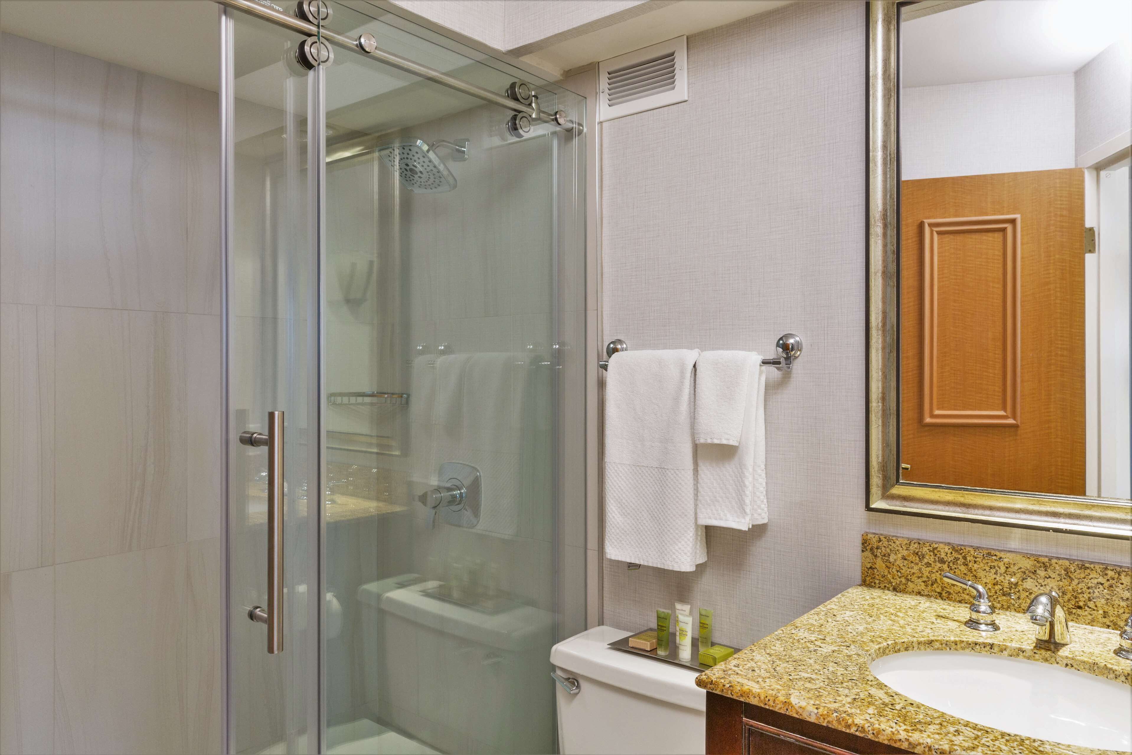 Un baño moderno con ducha de vidrio, inodoro y lavamanos con encimera de granito.