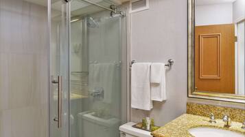 Un baño moderno con ducha de vidrio, inodoro y lavamanos con encimera de granito.