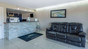 Un área de recepción con mostrador de piedra, sofá de cuero negro y un cuadro en la pared.