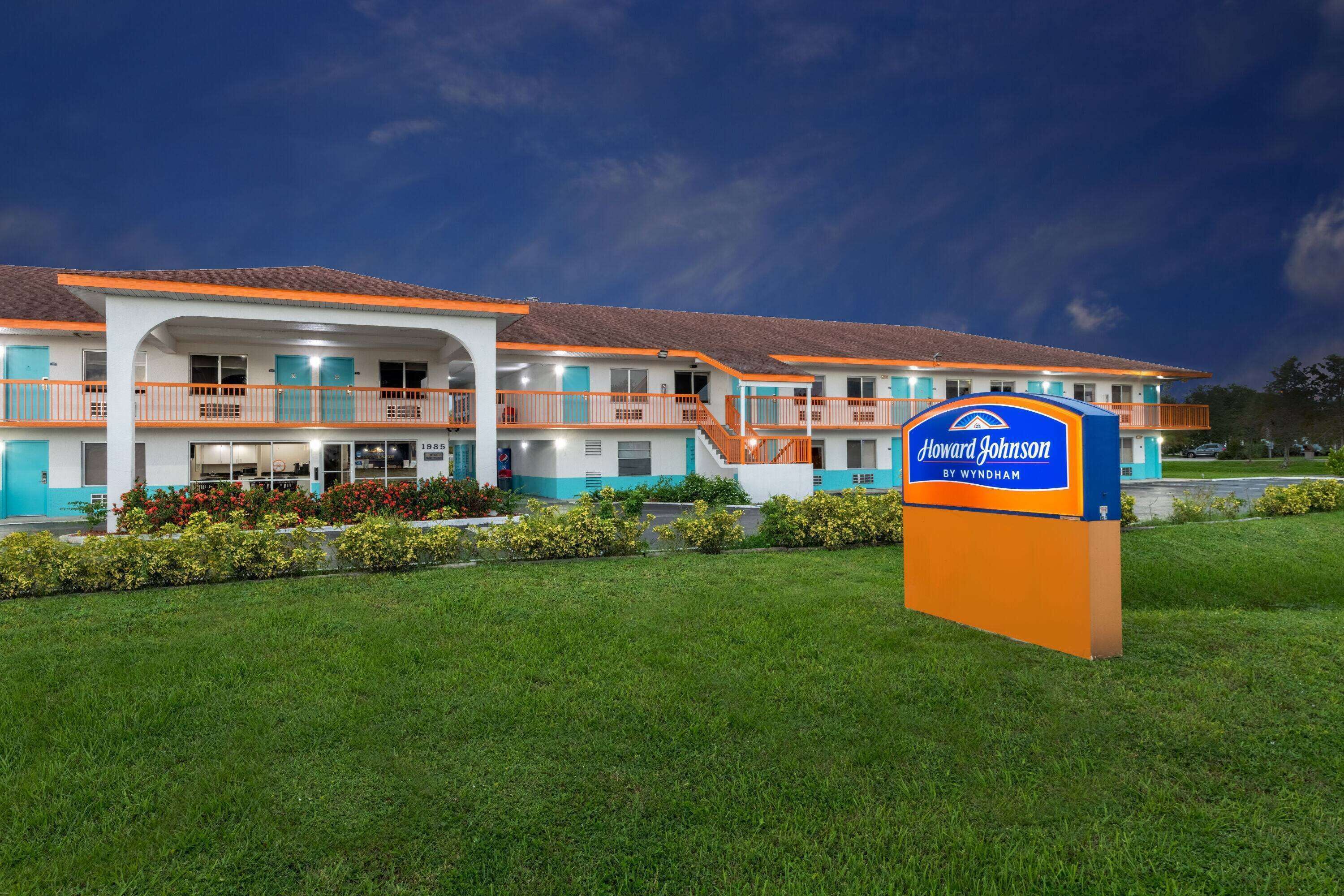 Ein Howard Johnson Motel mit zweistöckiger Bauweise, mehreren Balkonen und einem gepflegten Rasen.