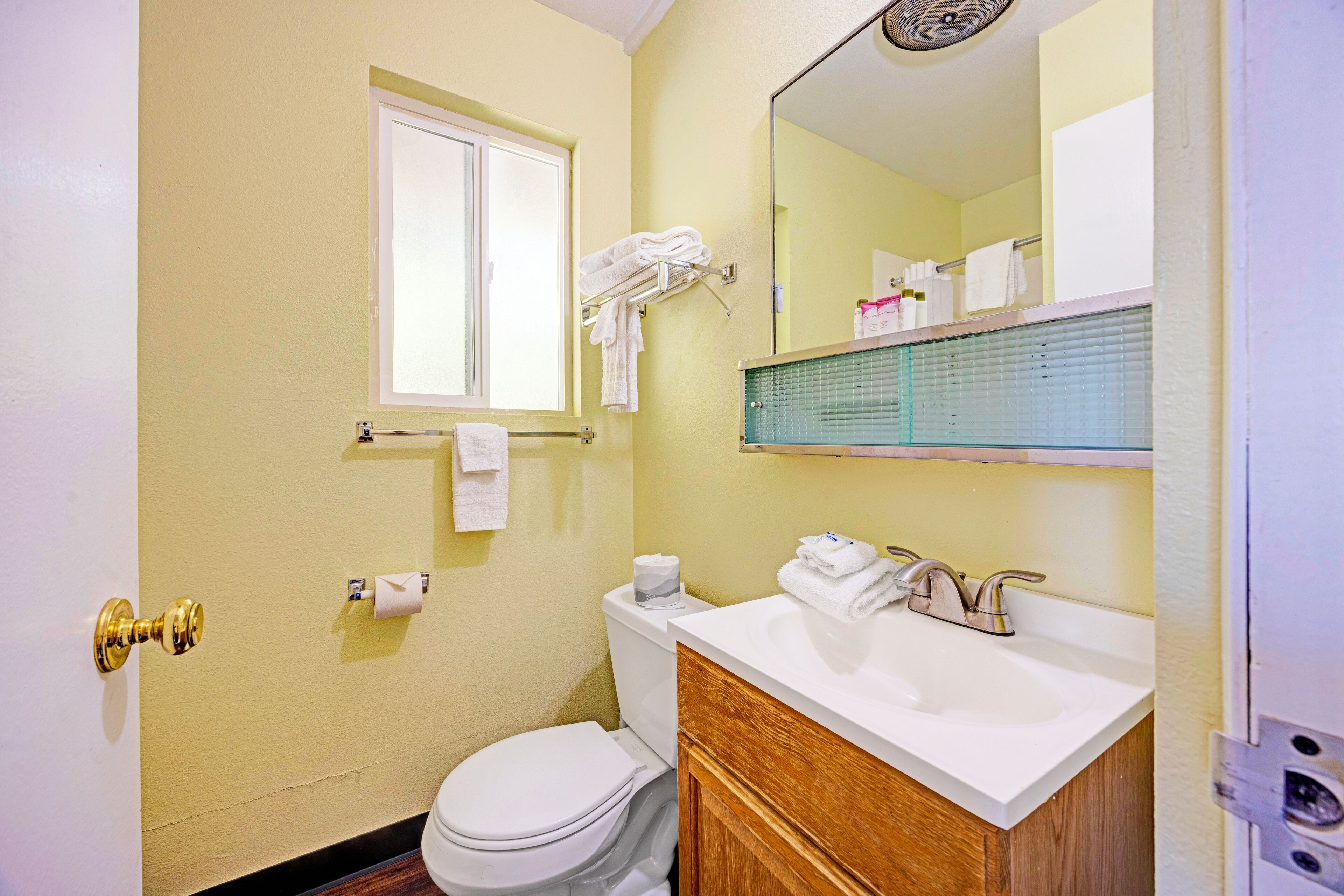 Un baño con inodoro, lavabo, espejo y perchero para toallas.