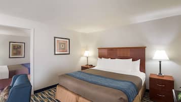 Habitación de hotel con una cama grande, dos mesitas de noche con lámparas, un sillón azul y una alfombra estampada.