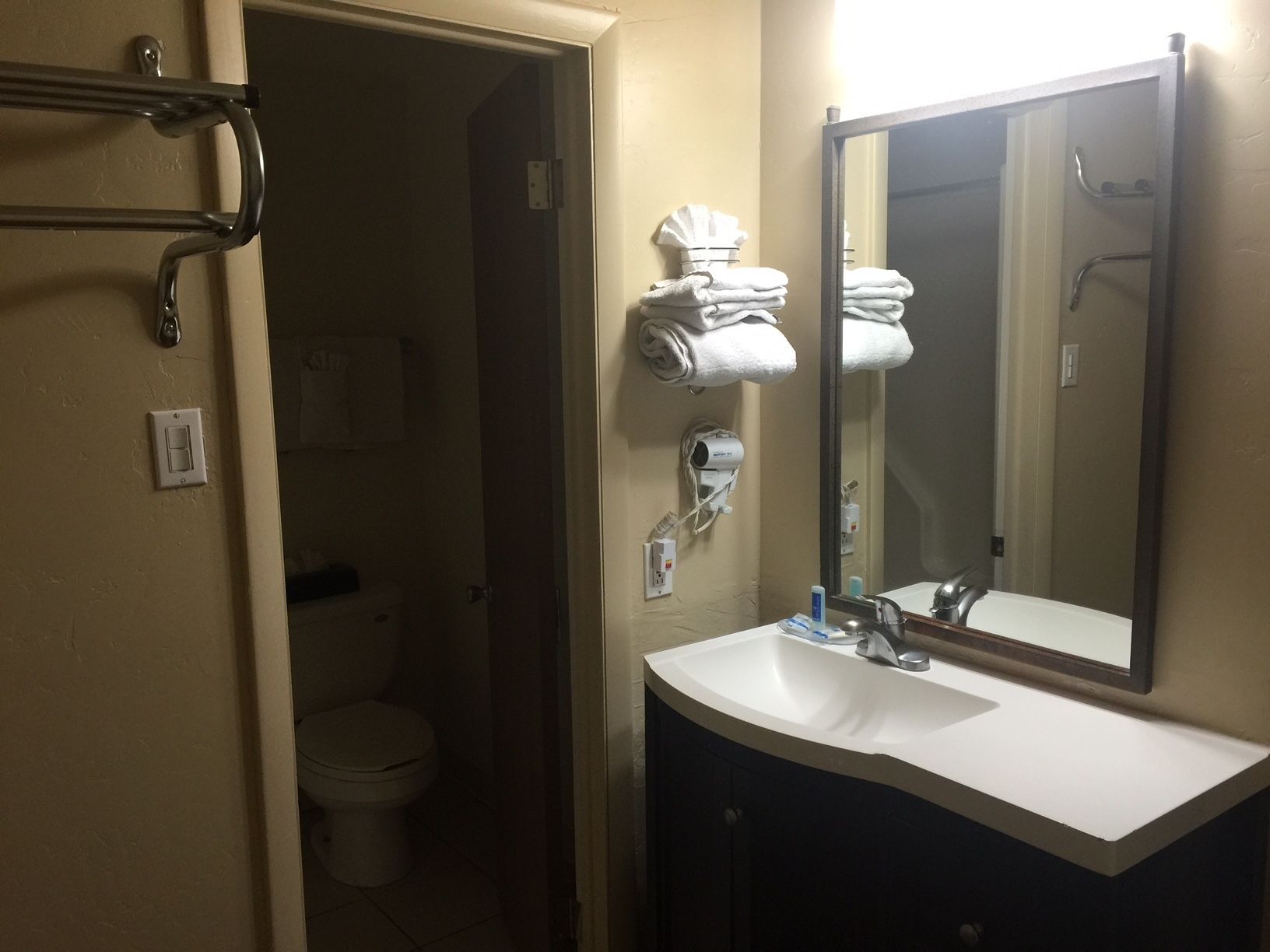 A bathroom with a white sink, a mirror, a towel rack, and a toilet.