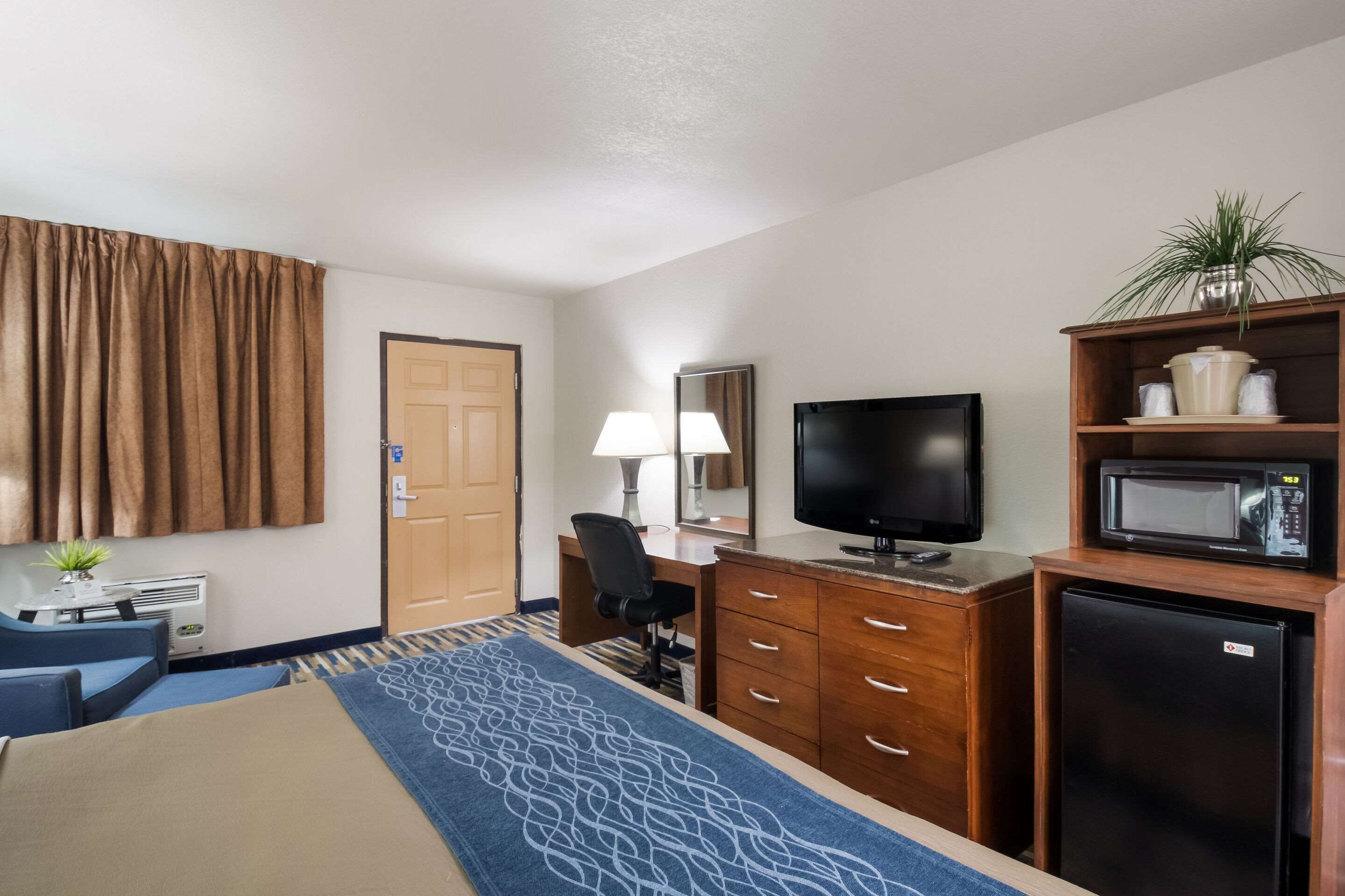 Habitación de hotel con cama, escritorio, televisión, refrigerador y microondas.