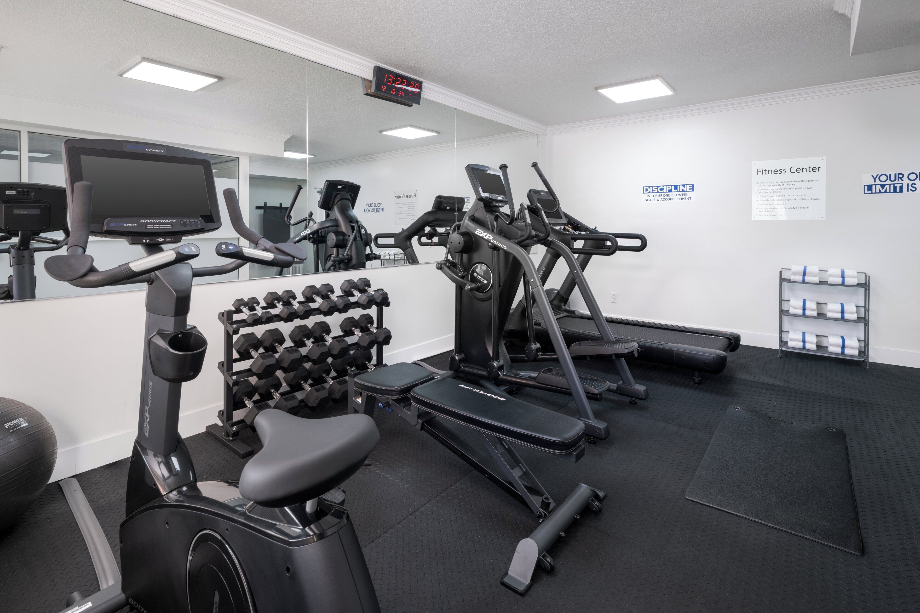 A fitness center with exercise equipment, a digital clock, and motivational posters.