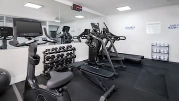A fitness center with exercise equipment, a digital clock, and motivational posters.