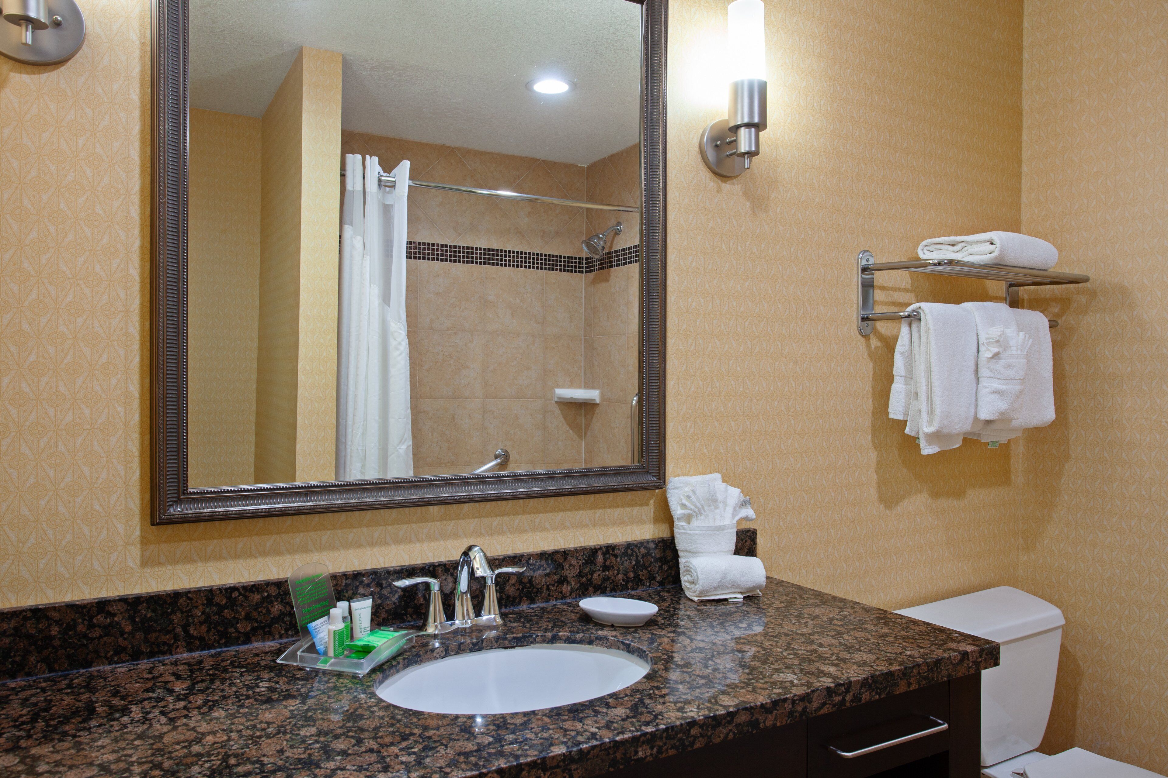 A bathroom with a granite countertop, white sink, and a large mirror.