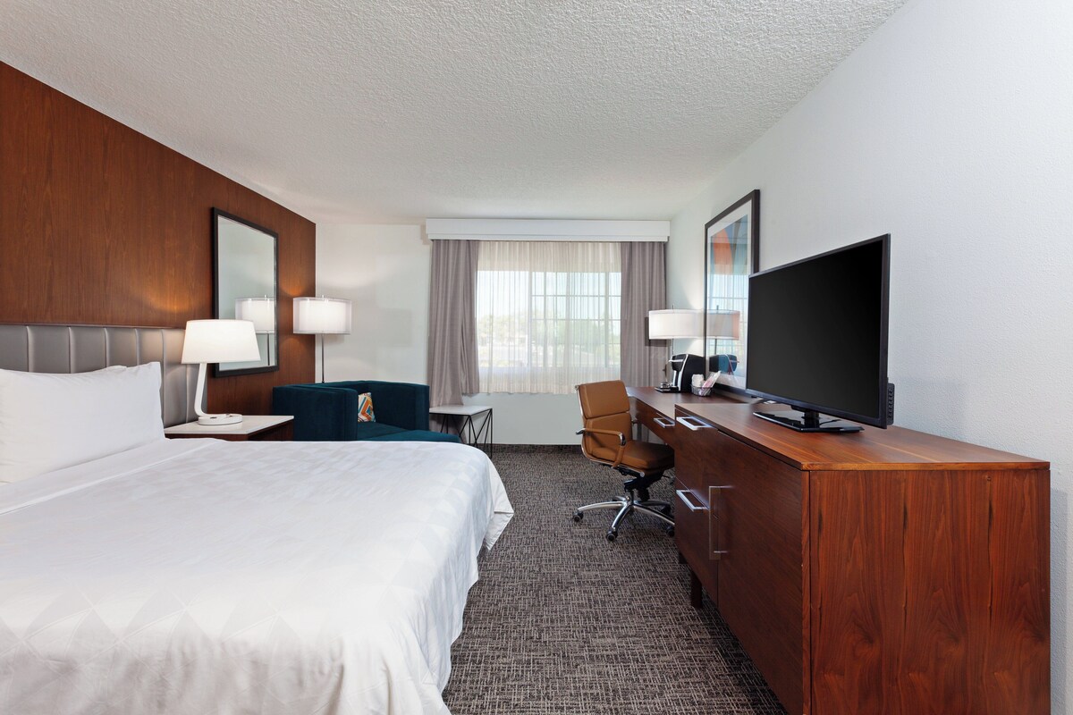 Een hotelkamer met een groot bed, een bureau, een televisie en een stoel.