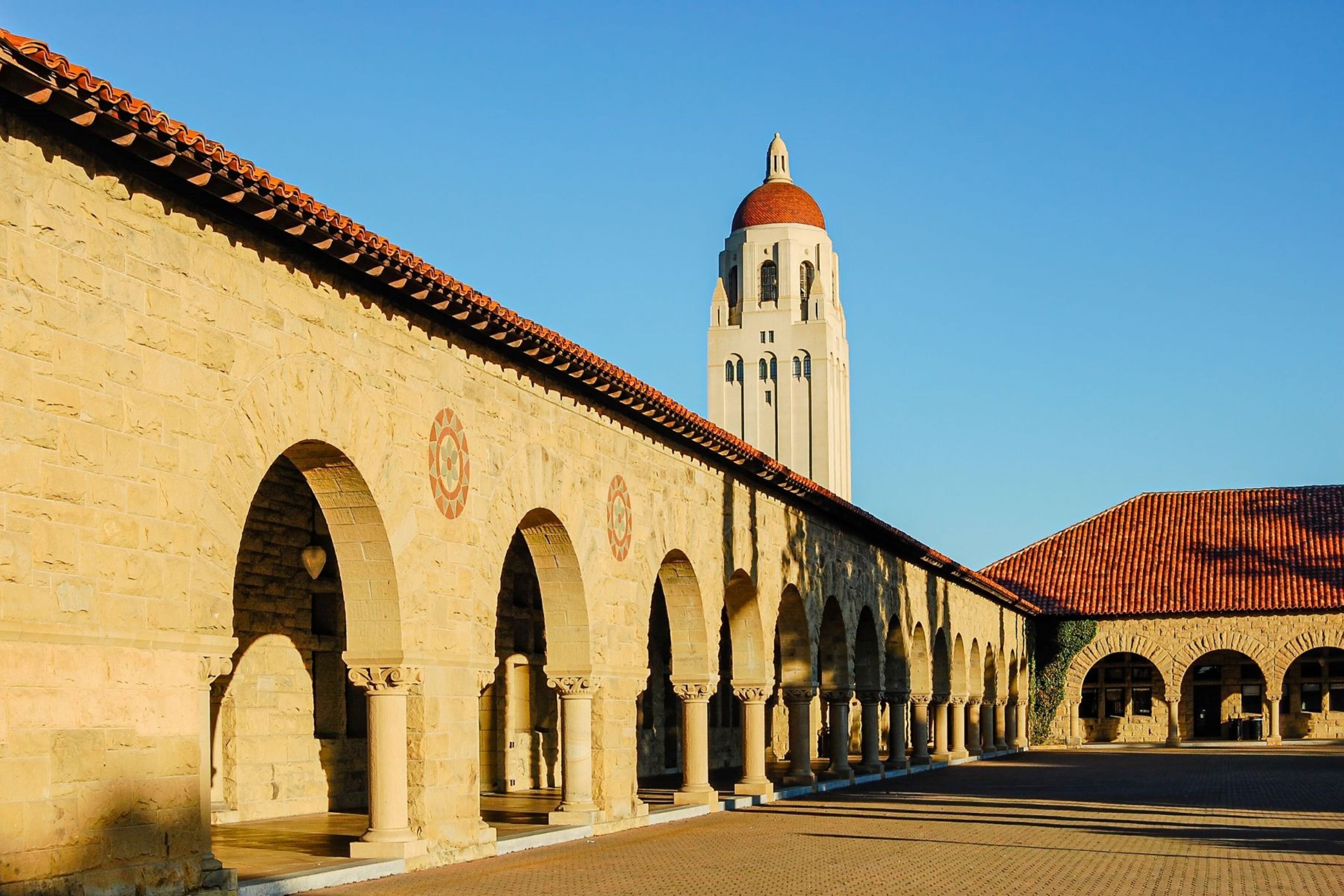 A historic building with a series of arches and a prominent tower with a red dome.