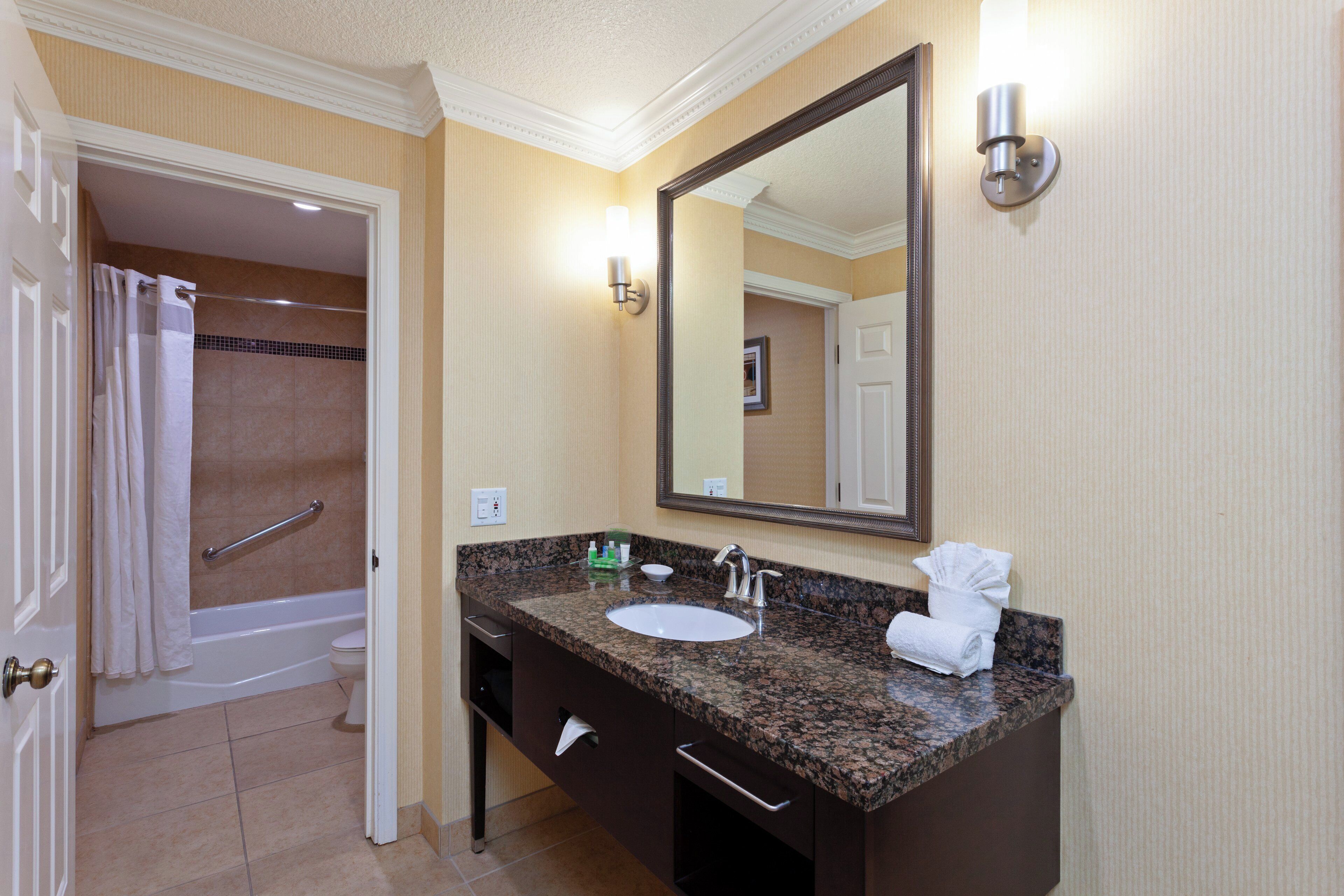 A bathroom with a sink, mirror, towel rack, and a shower area.