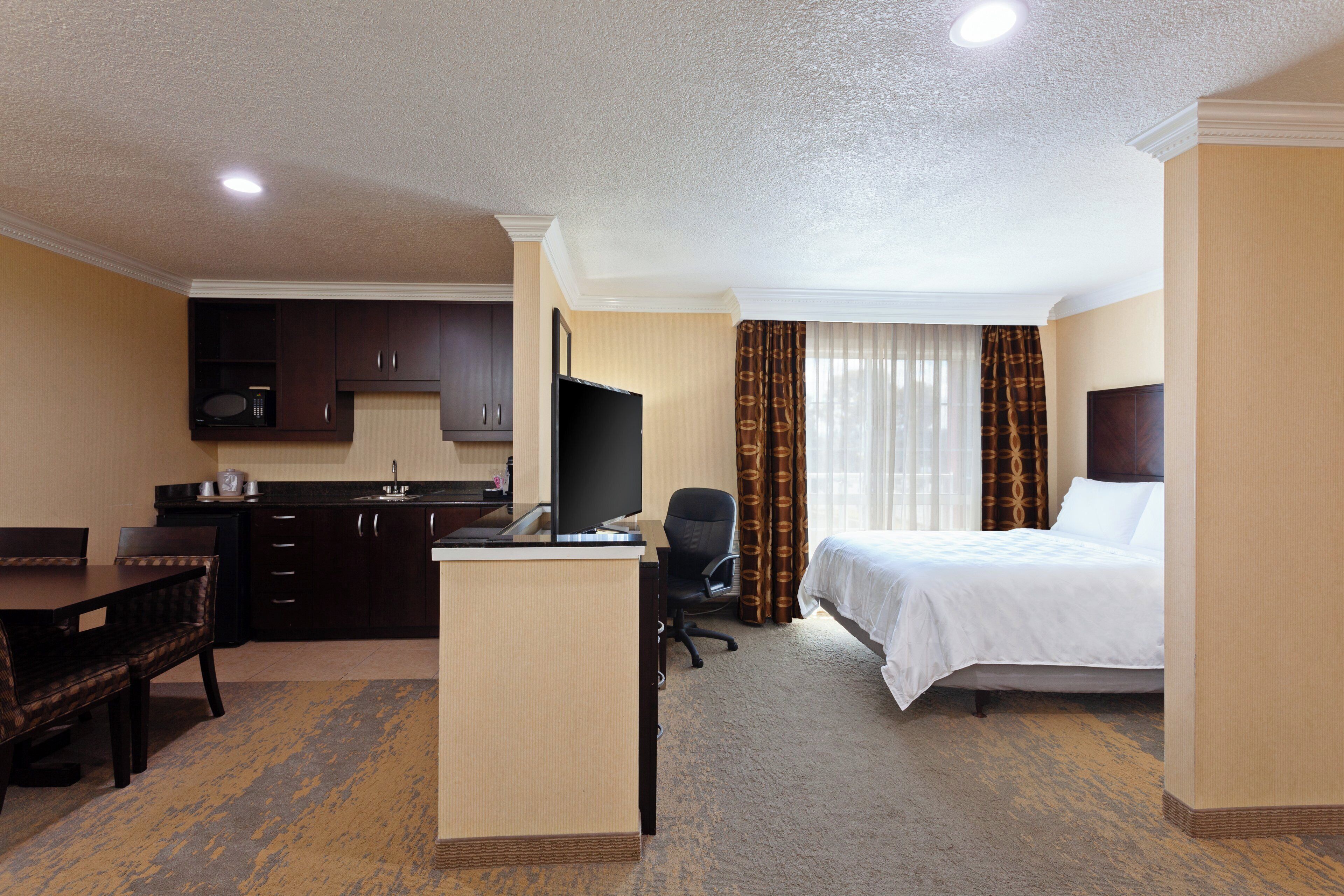 A hotel room with a bed, a desk, a chair, a television, and a microwave.